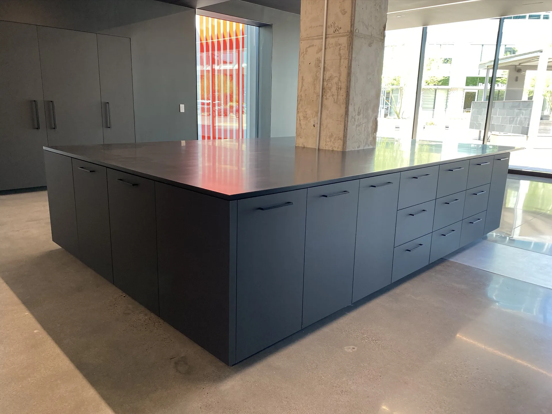 A black casework island with banks of drawers in a light-filled commercial space