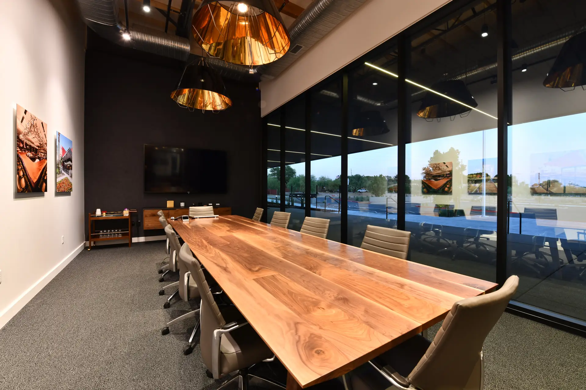 A long solid walnut conference table with leather chairs in a glass-walled boardroom